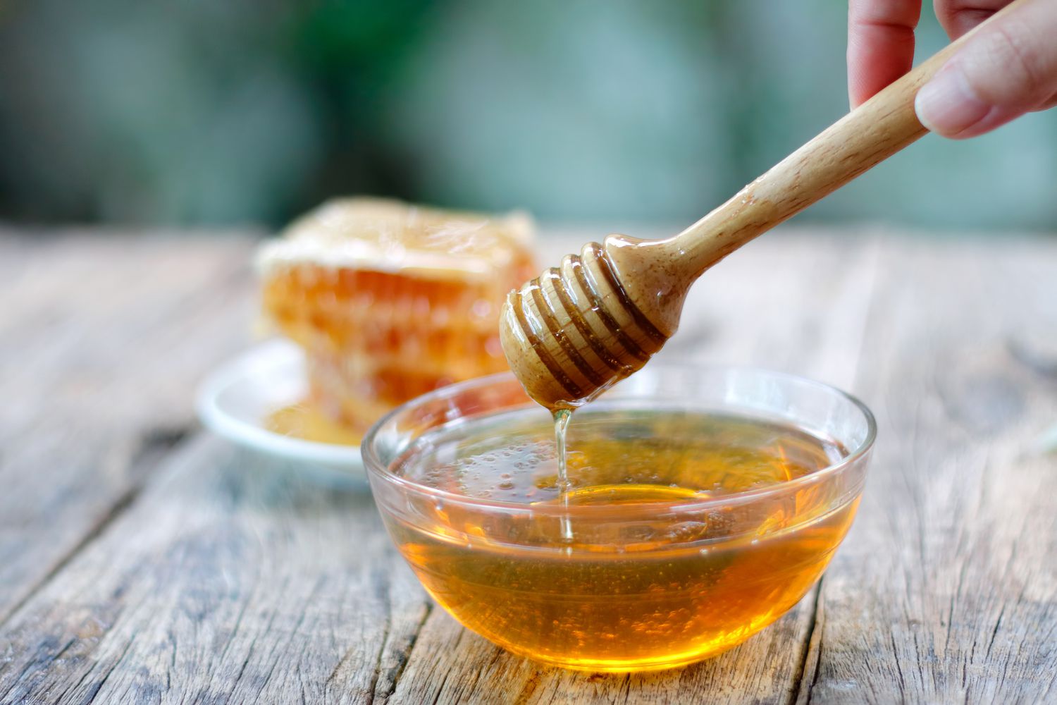 Raw Australian Manuka honey drizzled from a dipper over a honeycomb